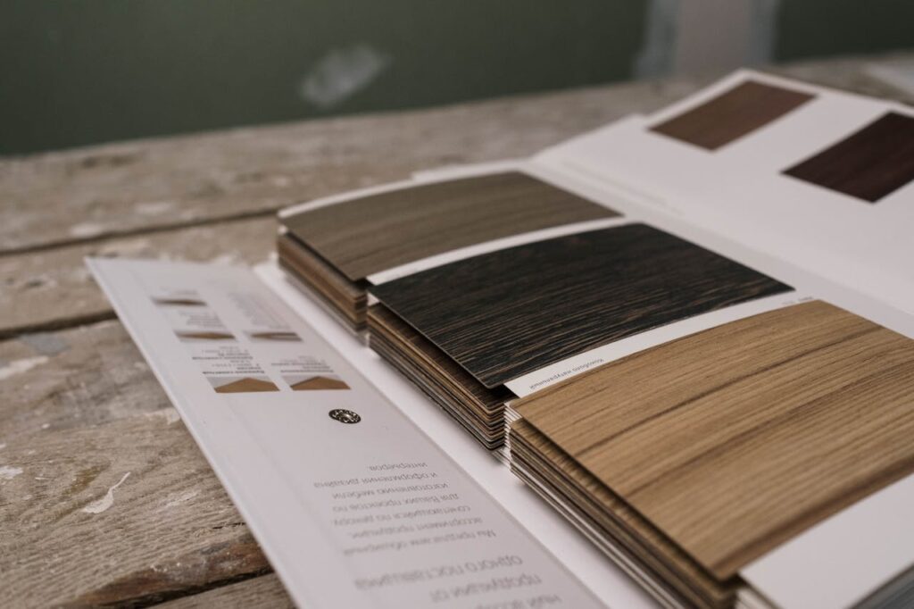 Collection of wood veneer samples displayed on a rustic wooden table indoors.